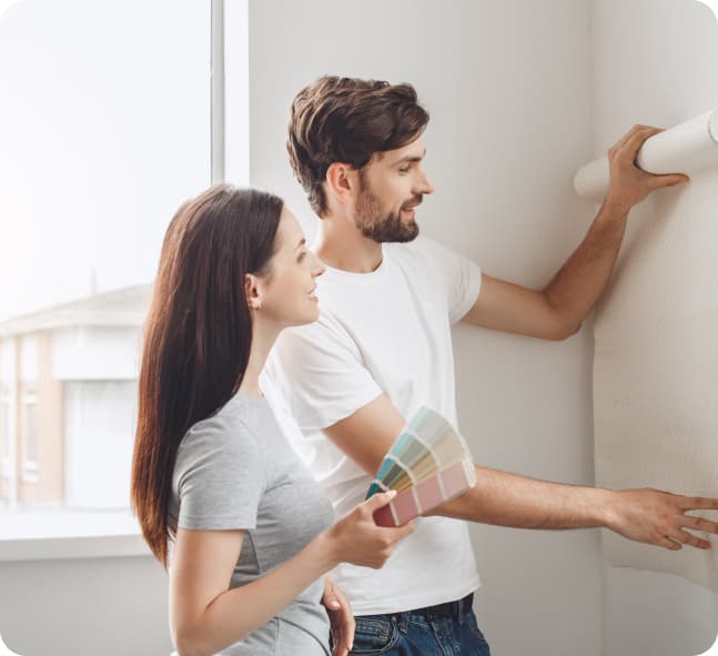 stock photo of man and woman putting up wallpaper